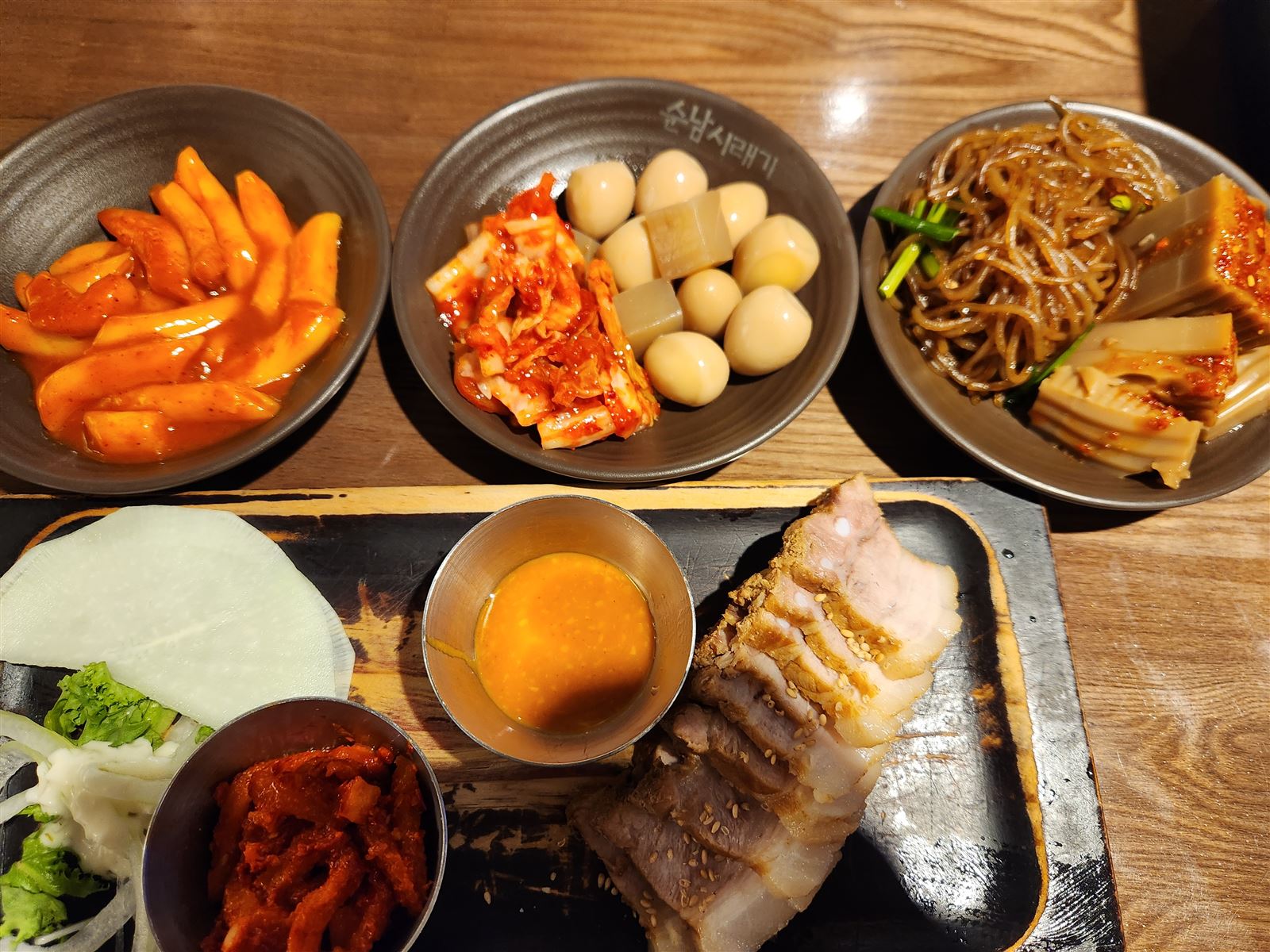 순남시래기 명동店砧板上的水煮豬肉切片，配包菜蔬菜與小菜